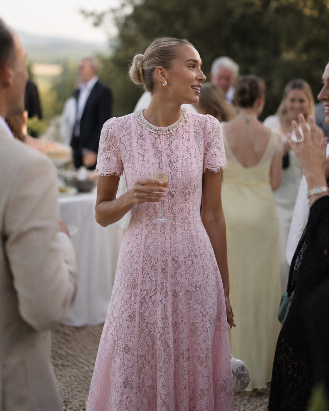 Woman wearing a textured pink dress at an outdoor garden reception