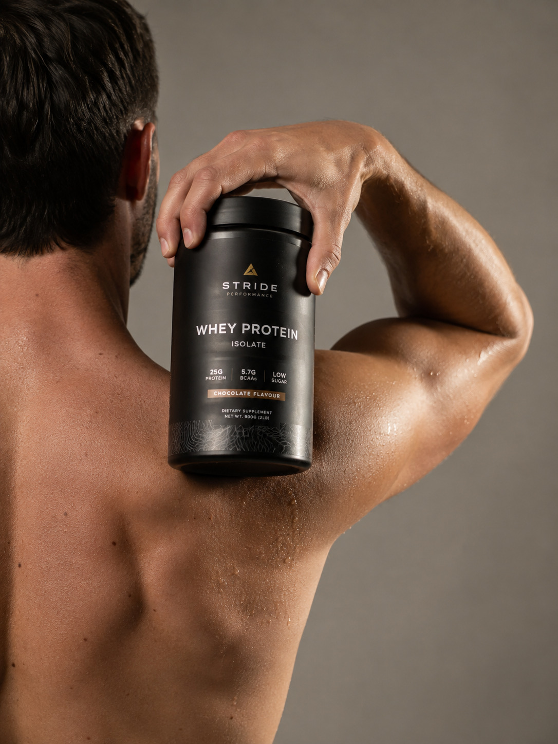 Athletic man holding a black protein supplement tub over his shoulder